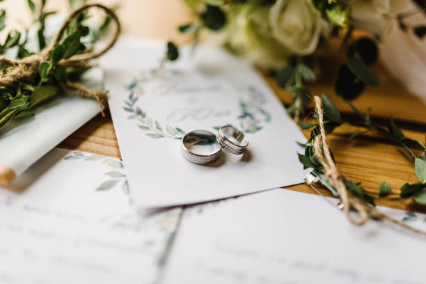 huwelijk Stylish rings, flowers on wooden table background. Letters from the bride and groom. Vows. Engagement. Luxury marriage and wedding accessory concept.